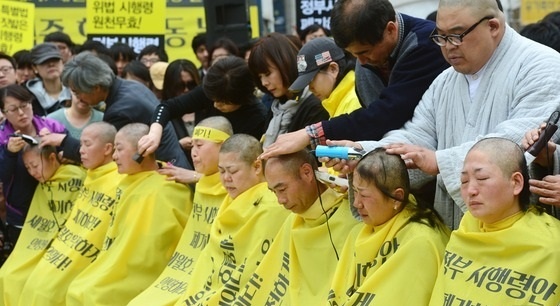 ↑ 세월호 유가족들이 2일 오후 서울 광화문광장에서 열린 정부의 세월호 피해자 배상과 보상금 지급 기준에 대한 공식 입장발표 기자회견을 마치고 세월호 특별법 시행령 폐지와 인양을 촉구하는 삭발식을 거행하고 있다. 유가족들은 이날 기자회견에서 