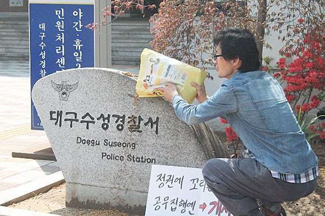 ▲ 지난 4월 21일 대구 수성경찰서 표지석에 개 사료를 뿌리는 박성수 씨 ⓒ평화뉴스(김영화)