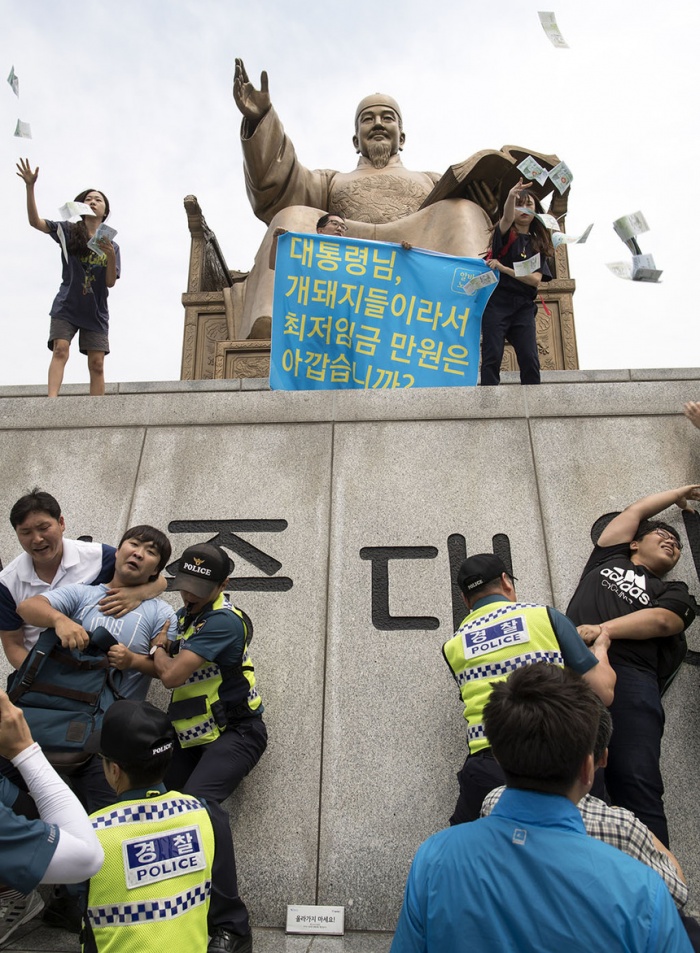 알바노조 소속 조합원들이 '최저 임금 1만원 인상'을 요구하며12일 오전 서울 세종로 광화문광장에 있는 세종대왕 동상위로 올라가고 있다. 