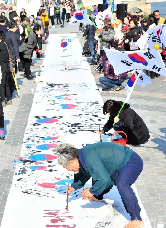 ▲ 제98주년 3.1절을 앞두고 서예가 김동욱씨가 28일 오후 경북 포항시 북구 영일대해수욕장에서 태극기 퍼포먼스를 펼치고 있다.이날 퍼포먼스에는 시민 100여명이 참가해 광목천에 붓으로 태극기를 그리며 3.1정신을 되새겼다