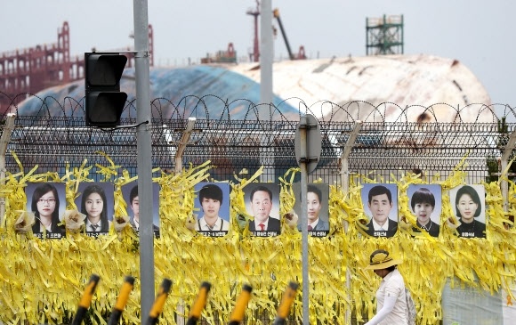 ▲ 모두 찾을 때까지 세월호 미수습자를 찾기 위한 객실 구역 1차 수색이 63일 만에 마무리된 20일 전남 목포신항 세월호 거치 장소 앞에 미수습자 사진들이 걸려 있다. 미수습자 9명 가운데 수색 기간 동안 4명의 유해를 찾았다.