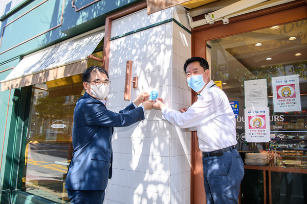 장충남 남해군수(왼쪽)가 21일 오후 착한 임대인 운동에 참여한 남해읍 소재 제10호 착한 임대인 상가를 방문해 ‘착한 나눔상가 스티커’를 부착하고 있다./ⓒ남해군