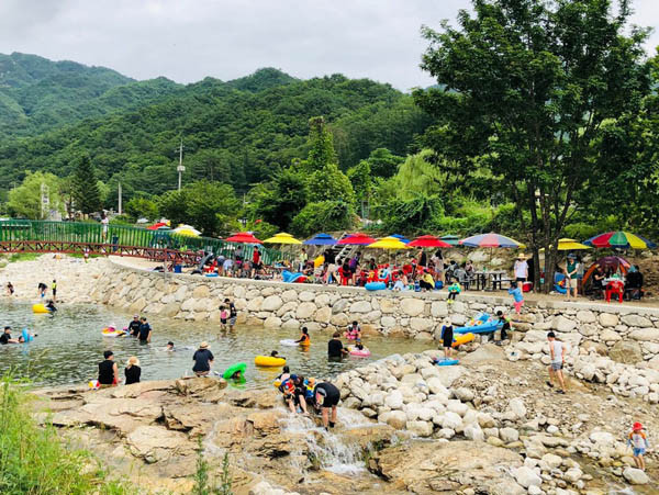 편의시설(파라솔) 설치 등 청정하게 바뀐 포천 백운계곡에서 물놀이를 즐기는 피서객들.(사진=경기도북부청]