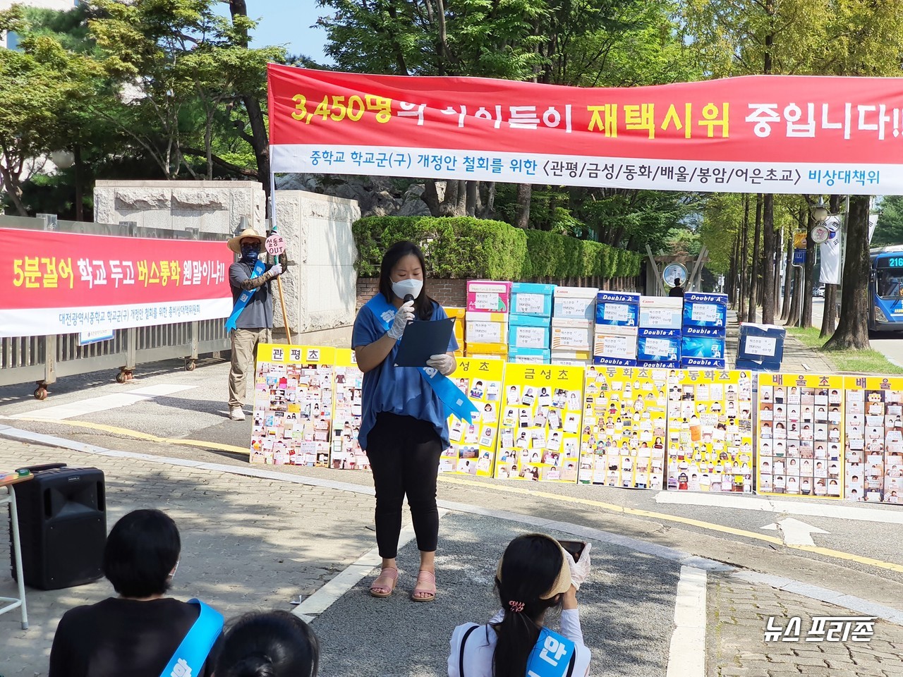 대전광역시 중학교 학군(구) 개정안 철회를 위한 총 비상대책위원회가 19일 오전 10시쯤 대전시교육청 후문 앞에서 "5분걸어 학교 두고 버스통학 웬말이냐", "3,450명의 아이들이 재택시위 중입니다!"라는 플래카드를 세우고 시위를 벌이고 있다./ⓒ이현식 기자