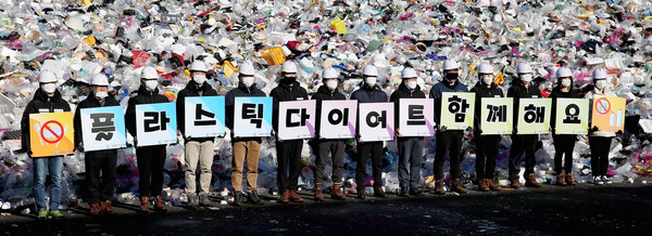 19일 오전 수원시자원순환센터 플라스틱 야외적치장에서 수원도시공사 임직원들이 ‘고고 릴레이’ 캠페인의 일환으로 ‘플라스틱 다이어트 함께해요’란 글이 새겨진 피켓을 선보이는 퍼포먼스를 하고 있다. 수원도시공사