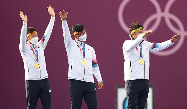 26일 도쿄올림픽 남자 양궁 단체전에서 우승한 (왼쪽부터) 김제덕, 김우진, 오진혁 선수가 일본 유메노시마 공원 양궁장 시상대에서 응원석을 향해 손을 흔들고 있다./ ⓒ연합뉴스