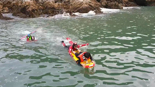 해경구조대원이 낚싯도구와 함께 고립자를 구조해 연안구조정쪽으로 헤엄쳐 접근하고 있다./©태안해양경찰서