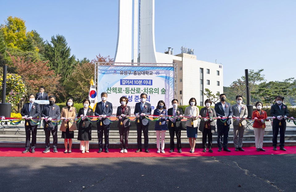 충남대학교와 유성구의 공통 공약인 지역민을 위한 ‘걸어서 10분 이내 산책로·등산로·치유의 숲 조성’ 준공식이 25일 열린 가운데, 충남대 이진숙 총장(왼쪽에서 6번째), 정용래 유성구청장(7번째) 등 관계자들이 컷팅 행사에 참여해 기념촬영을 하고 있다.(사진=충남대학교)