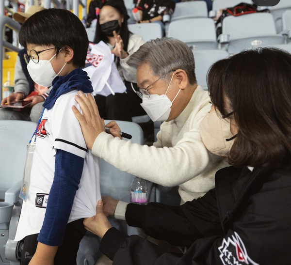 이재명 후보가 야구를 보러온 어린 소년이 사인을 요청하자 등에 사인을 하고 있다.(사진=이재명 후보 열린선거캠프)