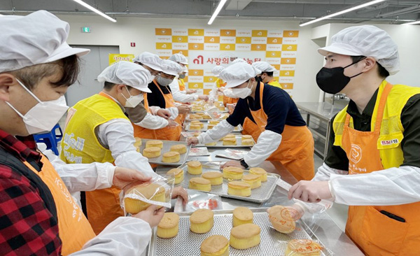 SM우방 임직원들이 대구시 서구에 마련된 제빵소에서 제빵봉사를 하면서 행사관계자들과 담소를 나누고 있다.(사진=SM우방)